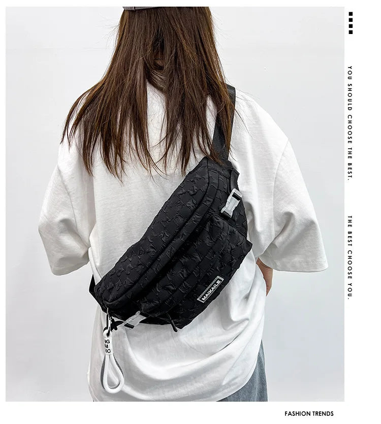 A person is shown from the back wearing a black plaid crossbody chest bag with an adjustable strap over a white t-shirt.