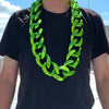 A man wearing a chunky, bright lime green acrylic Cuban link necklace around his neck.