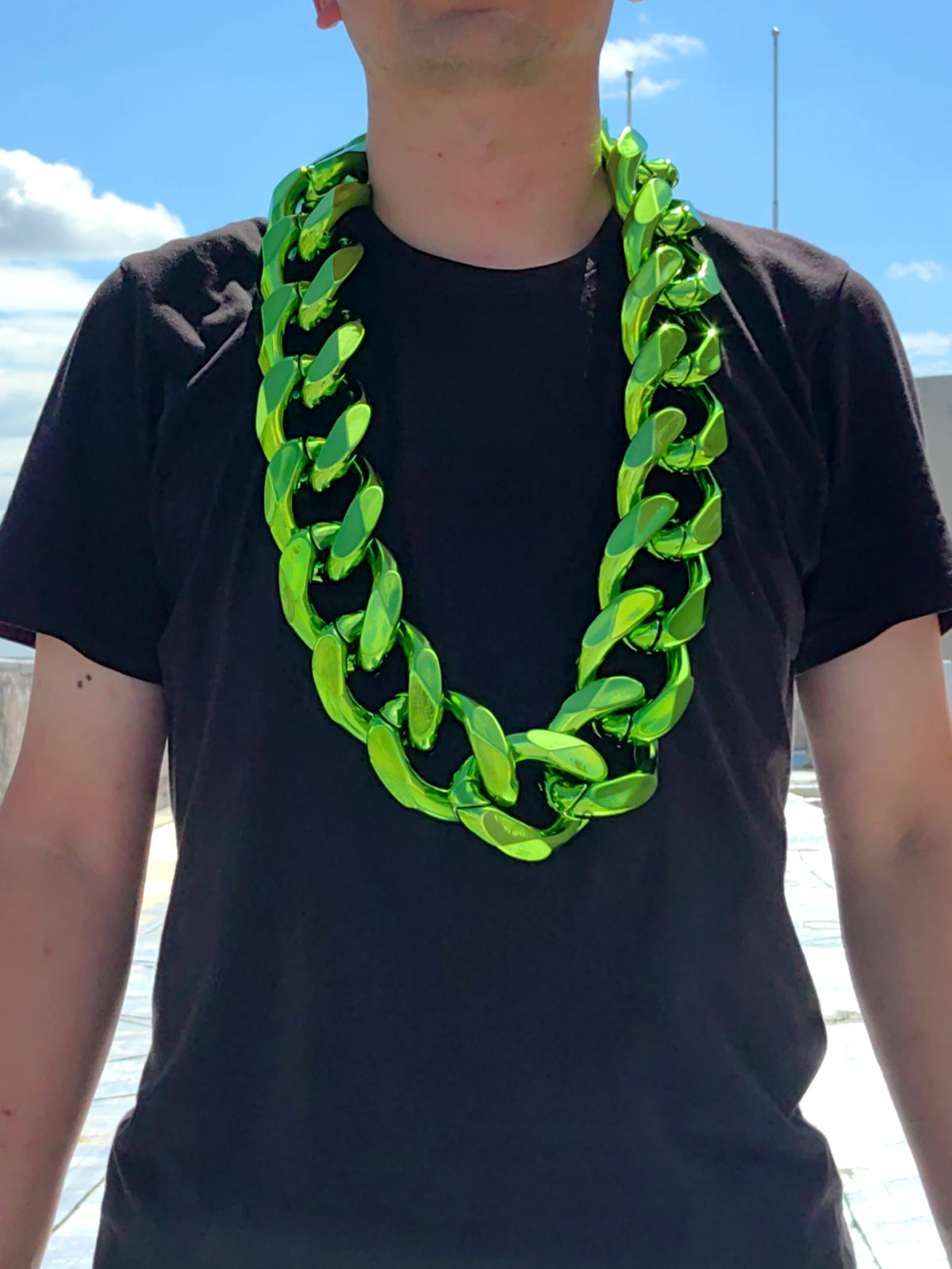A man wearing a chunky, bright lime green acrylic Cuban link necklace around his neck.