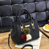 Black vintage PU leather tassel handbag with gold hardware resting on a wooden surface.