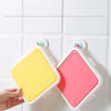 A hand holds a pink silicone reusable sandwich and lunch container against a white tiled background.