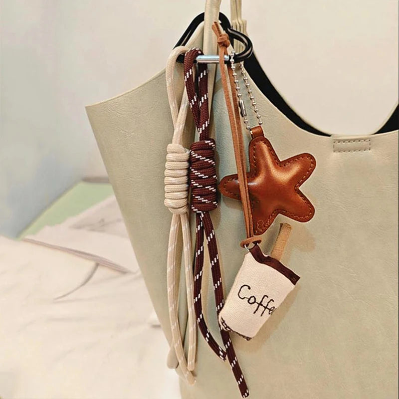 Un dije de cuero marrón en forma de estrella cuelga de una cadena beige, atada a una bolsa de lona verde claro.