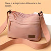 A light pink nylon crossbody shoulder bag with a zipper detail is shown against a neutral background.
