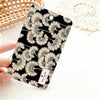 A black card holder featuring a repeating pattern of delicate, light beige flower illustrations.