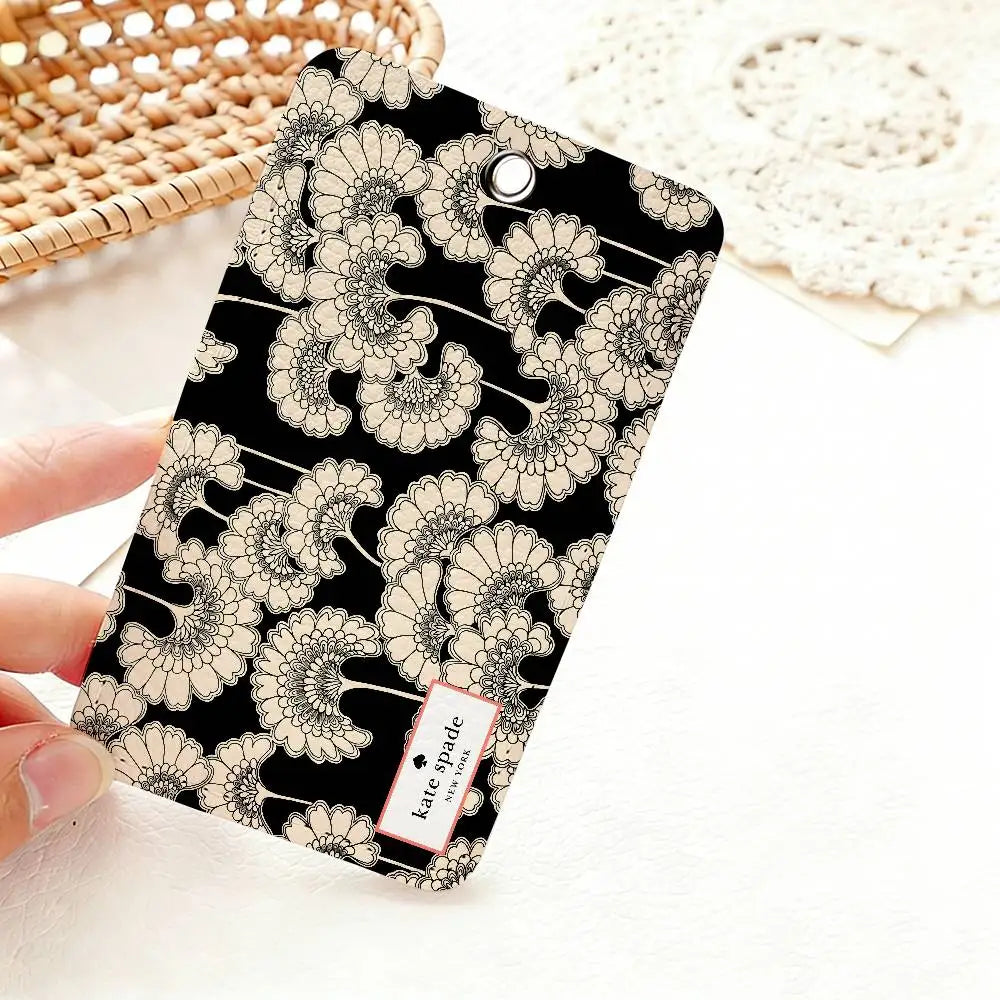 A black card holder featuring a repeating pattern of delicate, light beige flower illustrations.