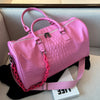 A pink crocodile grain PU leather travel duffle bag resting on a light-colored surface.