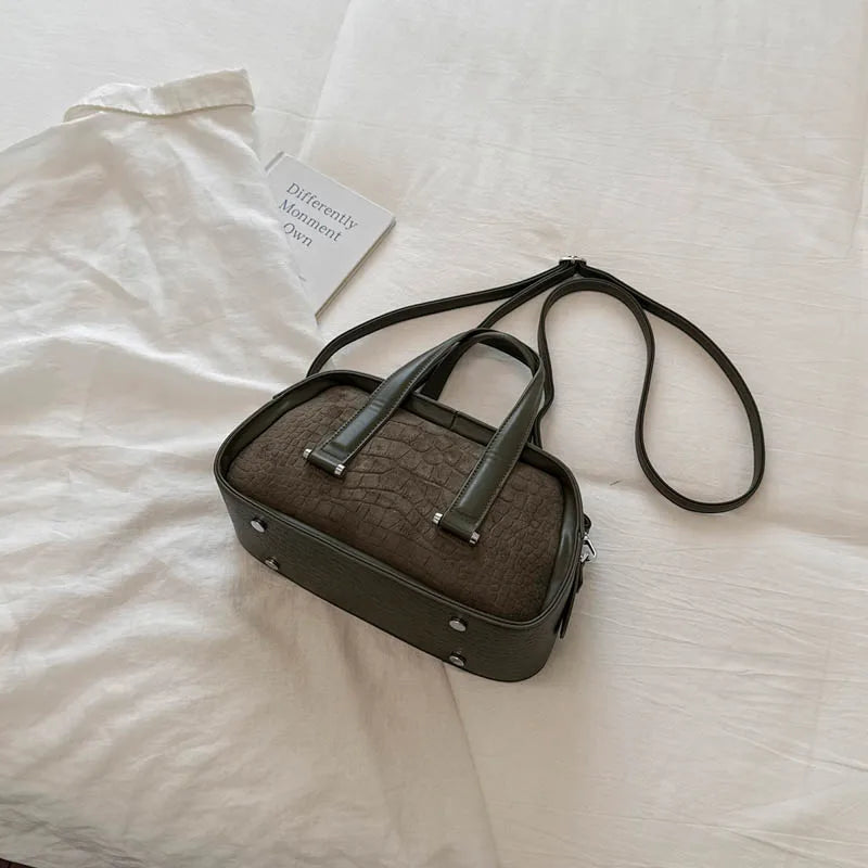 A dark olive green retro crocodile textured mini crossbody bag resting on a white fabric background.