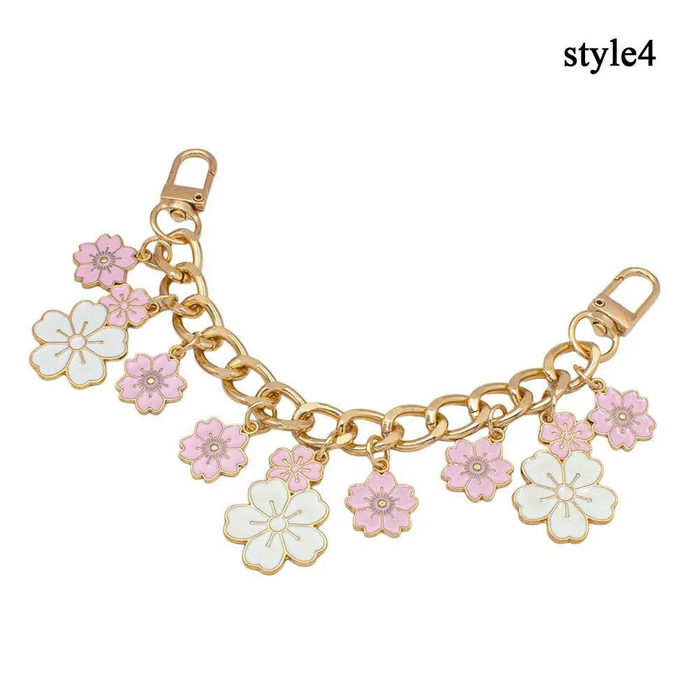 Accesorio de cadena para bolso tono dorado con flores de esmalte en rosa y blanco.