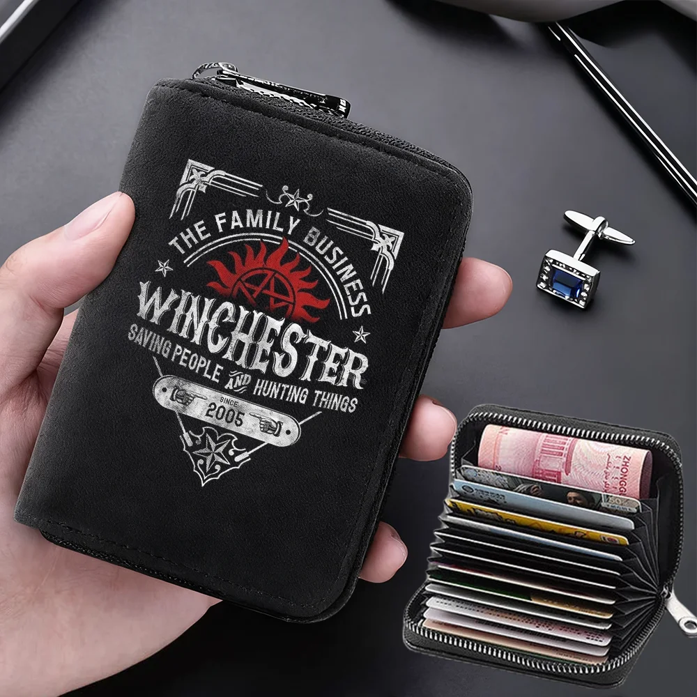 A black compact card wallet with a leather-like texture is shown being held by a hand, featuring a decorative design.