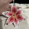 A realistic pink and white orchid flower keychain is held in a hand against a light background.