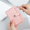 A hand holds a pink PU leather mini card holder wallet with a silver clasp against a white background.