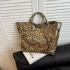 A brown leopard print transparent waterproof PVC tote bag resting on a black surface.