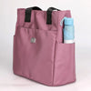 A mauve nylon shoulder tote bag with black straps and a blue water bottle in the side pocket.
