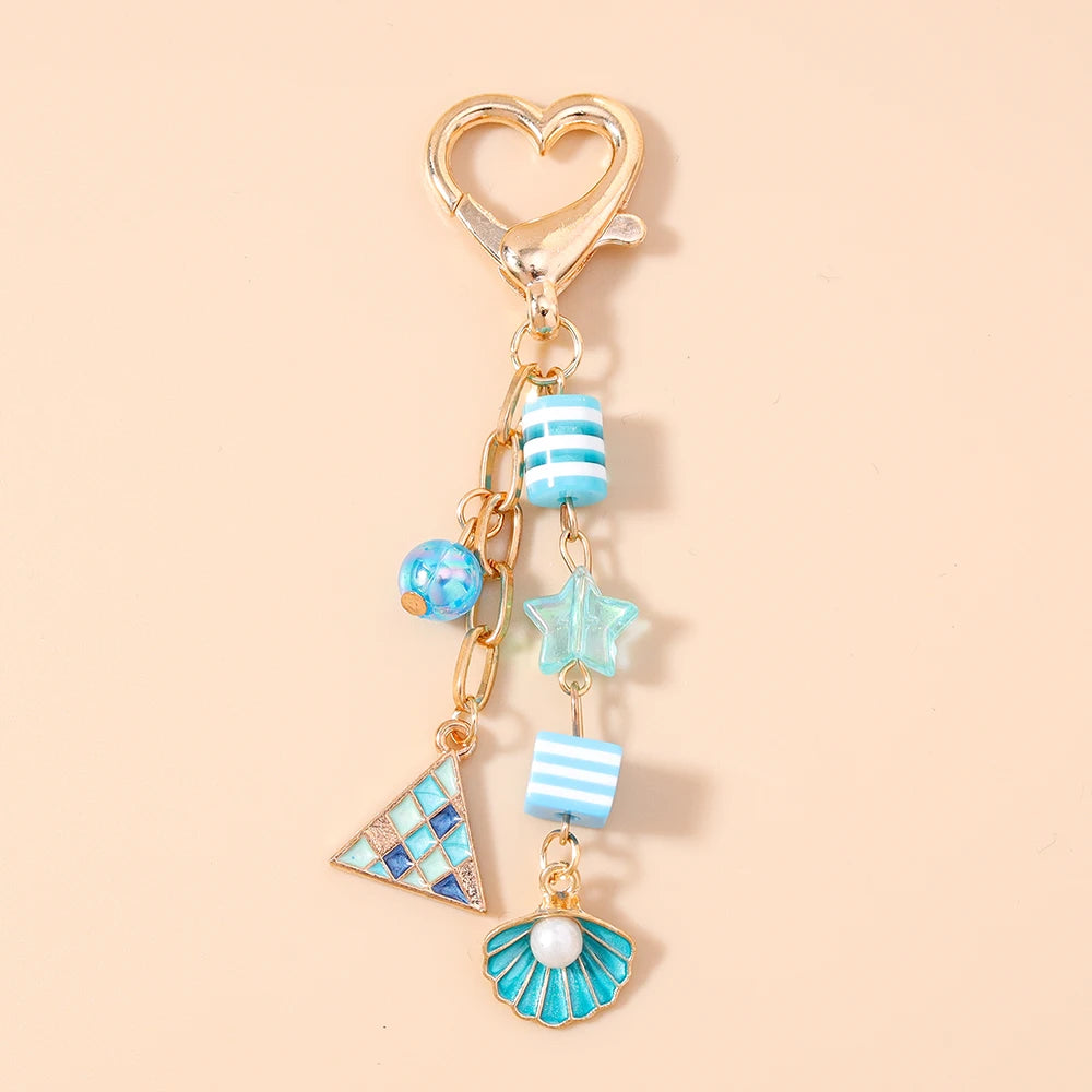 Gold-toned starfish keychain featuring blue and white striped beads, a star charm, and a pearl accent.