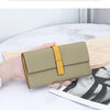 A beige genuine cow leather bifold wallet with a yellow accent is held in a hand on a white surface.