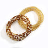 A close-up of colorful belly bead chains made of gold and amber beads.