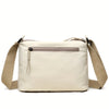 A cream-colored nylon crossbody shoulder bag with a zippered top compartment and tan strap.