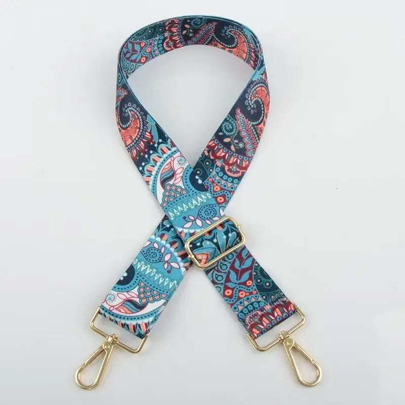 A patterned blue and pink nylon strap for bags and luggage with gold hardware.
