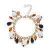 A gold charm bracelet featuring white and black pumpkin ghost charms.