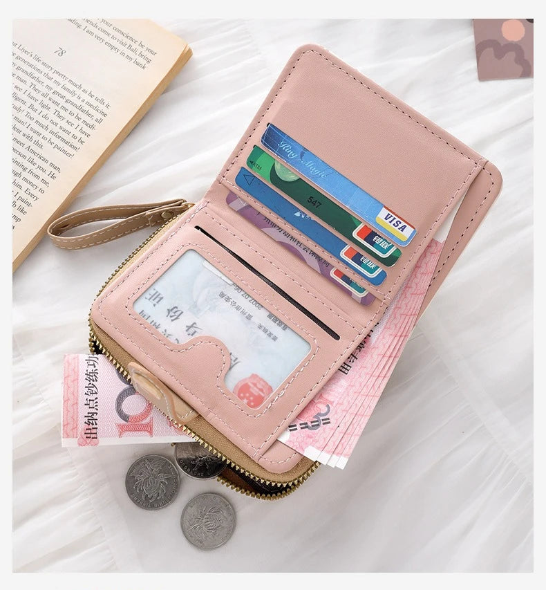 Pinkes Leder-Portemonnaie aus Kunstleder, geöffnet und mit Karten und Münzen auf einer weißen Fläche.