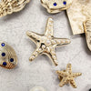 A collection of gold and silver ocean-themed shoe charms including a conch shell, starfish, and pearl.