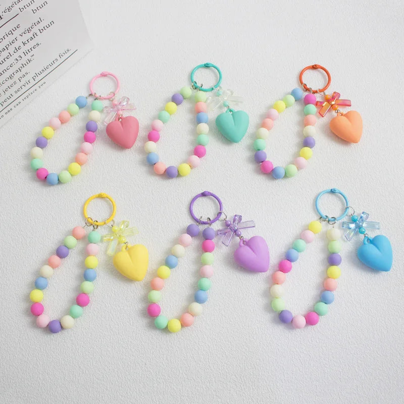 A collection of colorful bead keychains featuring hearts and bows on O-ring clips.