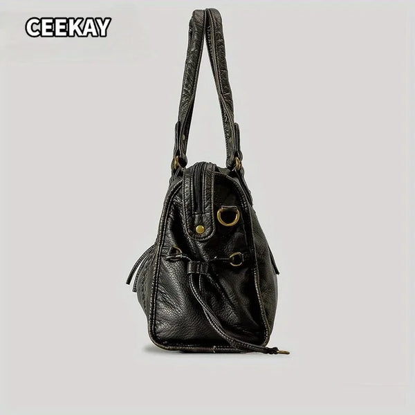 Bolso de cuero envejecido negro con solapa y herrajes dorados.