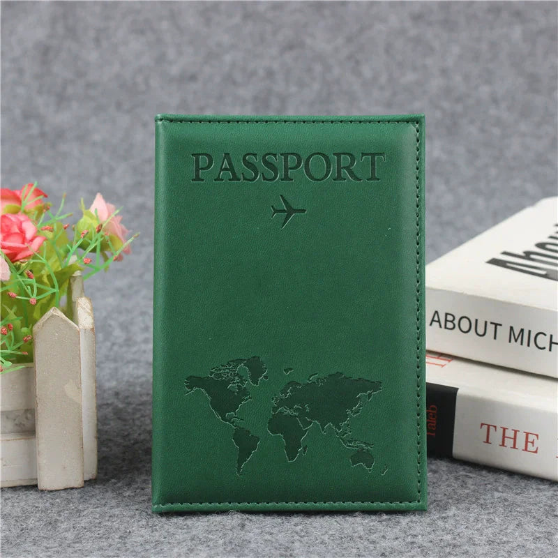 Couverture de passeport en cuir PU vert foncé, gravée d'une carte du monde et d'un avion, posée sur une surface grise.