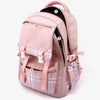 A pink canvas backpack with plaid accents and multiple zippered compartments.