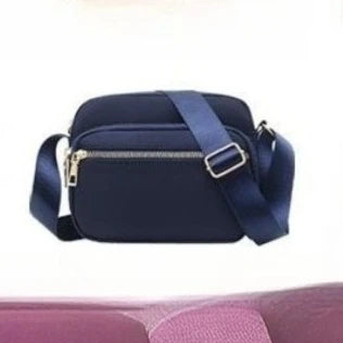 Navy blue compact oxford fabric crossbody bag with a gold zipper and dark blue strap