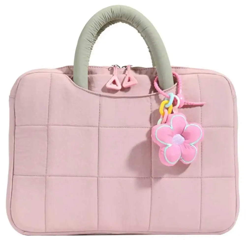 A pink quilted laptop sleeve with a light green handle and pink flower charm.