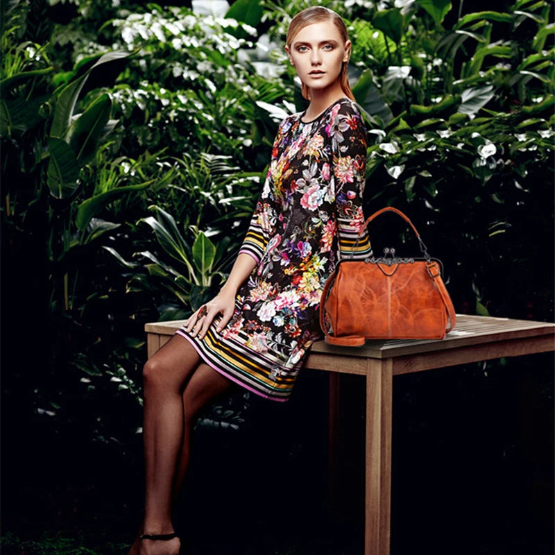 A woman models an elegant leather crossbody shoulder bag in a floral print dress outdoors.