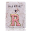 Portafolio de pasaporte marmolado rosa con inicial R dorada grabada en la parte delantera.