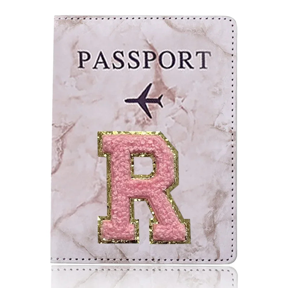 Portafolio de pasaporte marmolado rosa con inicial R dorada grabada en la parte delantera.
