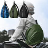 A person is wearing a black helmet with an attached green backpack, alongside various colored helmet bags.