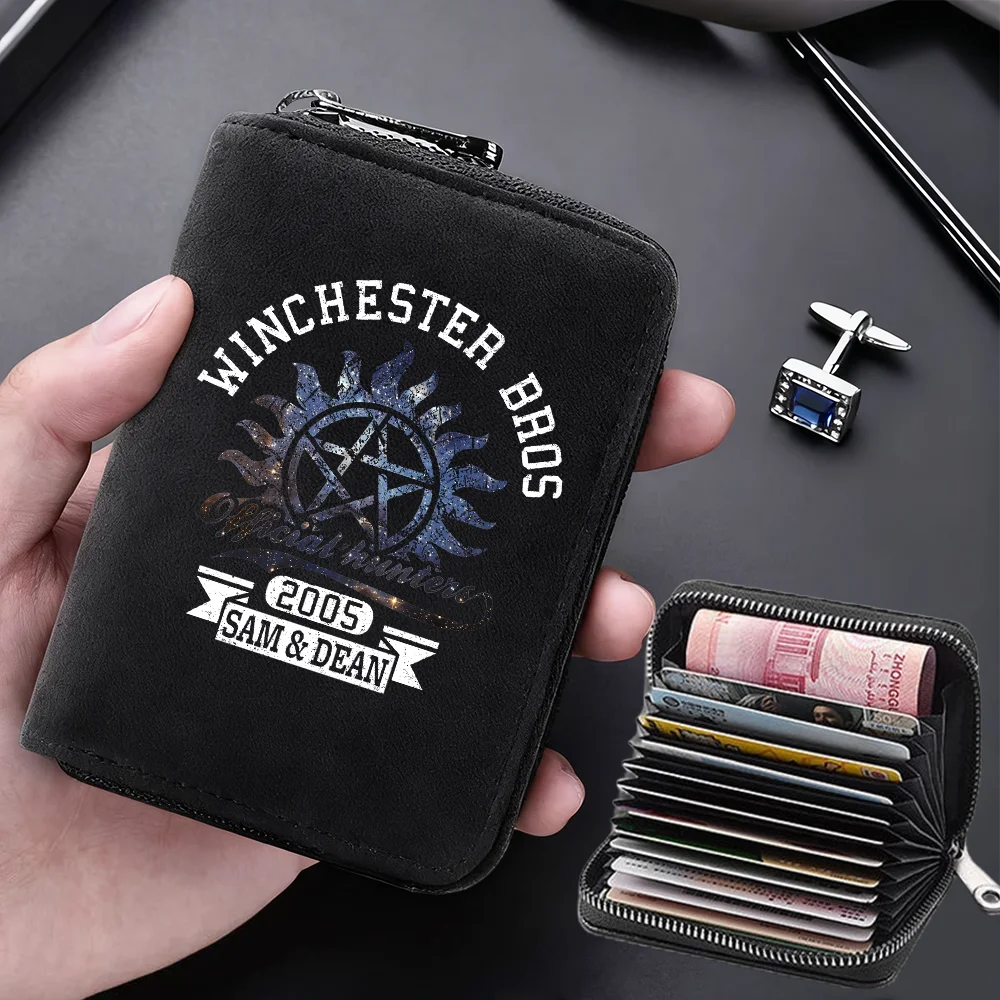 A black leather wallet with the text Winchester Bros and 2005 Sam & Dean is held in a hand next to a zippered card holder.