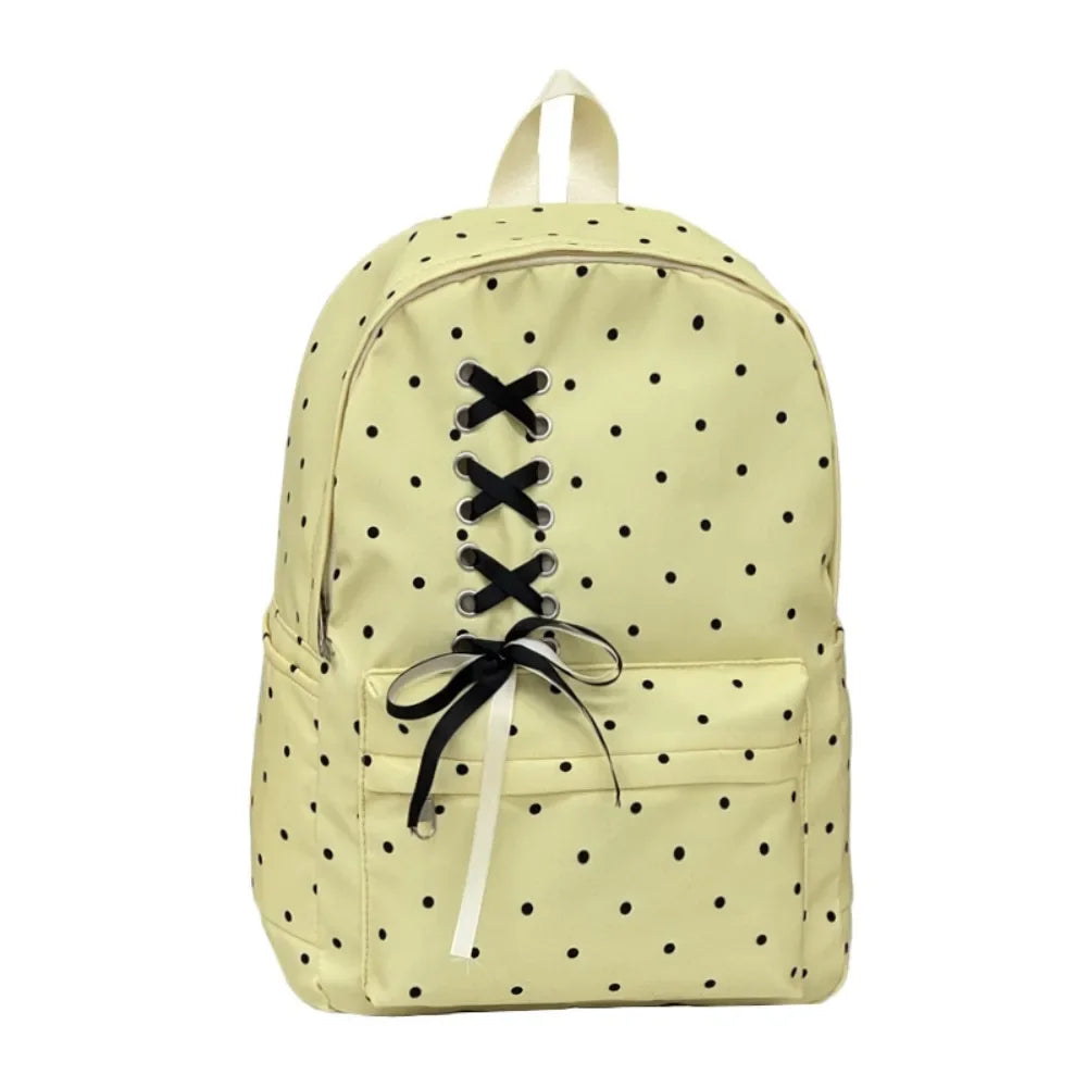 A light yellow corduroy backpack with a black bow print and drawstring closure.