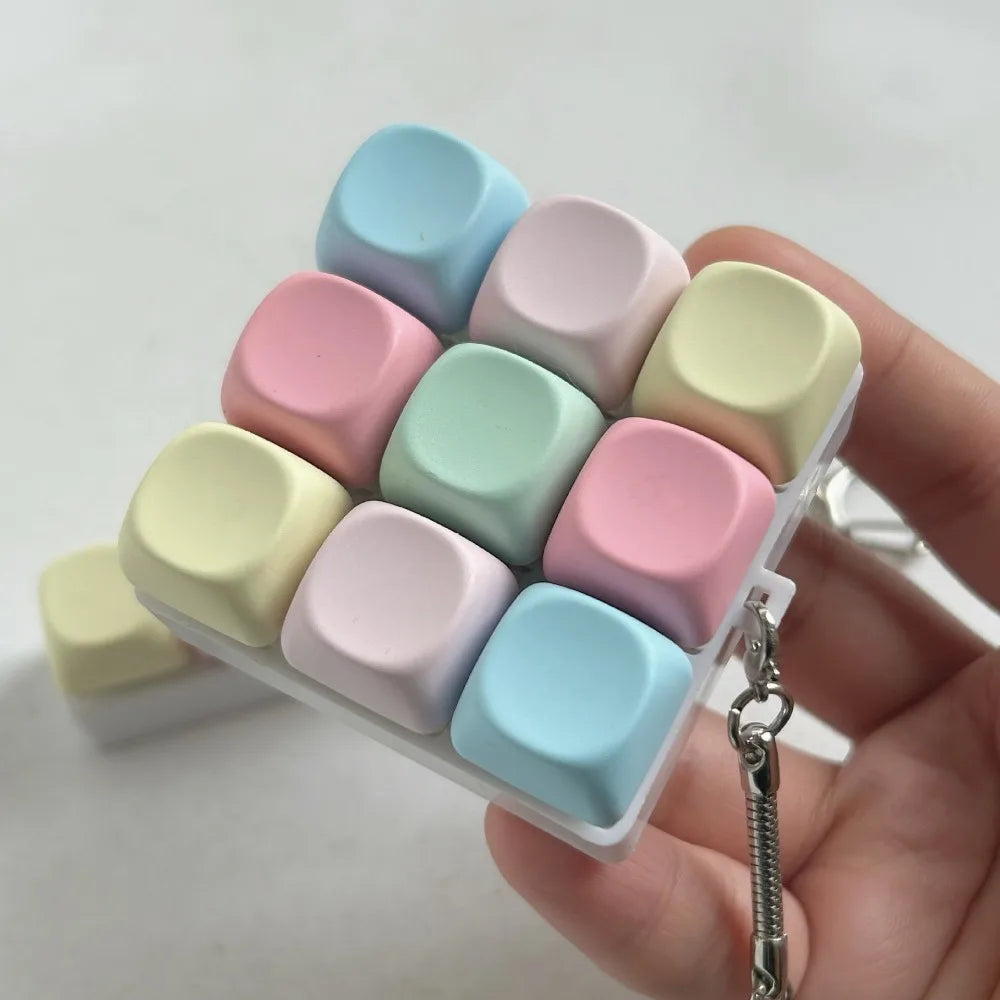 A hand holds a silicone tactile stress relief keyboard fidget toy with multiple pastel colored buttons.