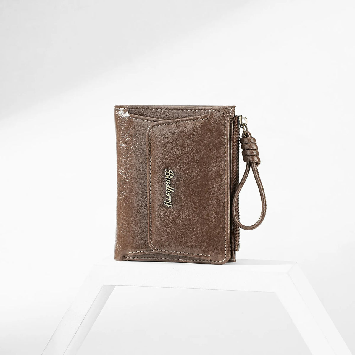 A brown leather mini wallet with a stitched design and a leather cord attached, shown on a white surface.
