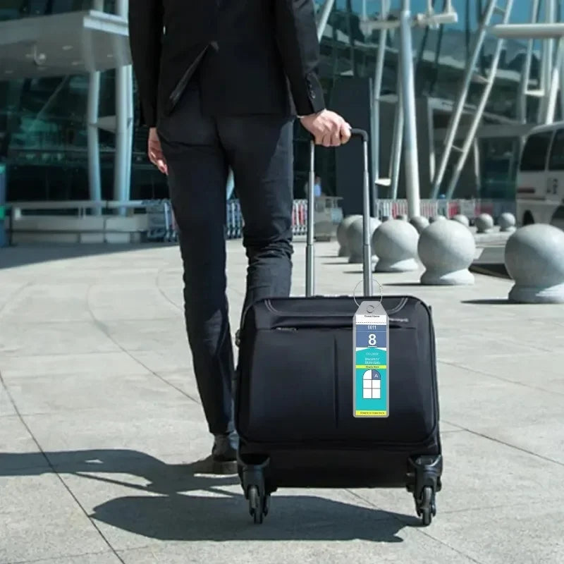 A person in a black suit is pulling a black rolling suitcase with a luggage tag across a paved outdoor area.