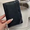 A black passport wallet is held by a hand on a clear glass table.