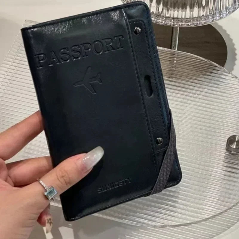 A black passport wallet is held by a hand on a clear glass table.