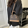 A woman holds a tan leather fashion shell shoulder crossbody bag with a checkered pattern against a light background.
