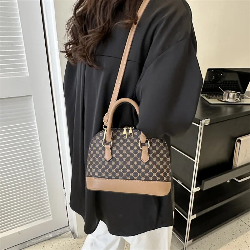 A woman holds a tan leather fashion shell shoulder crossbody bag with a checkered pattern against a light background.