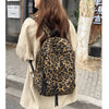 A woman wearing a beige shirt carries a leopard print canvas backpack outdoors.