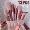 Una colección de trece brochas de maquillaje profesionales en varios tonos rosa y nude, guardadas en una bolsa de tela.