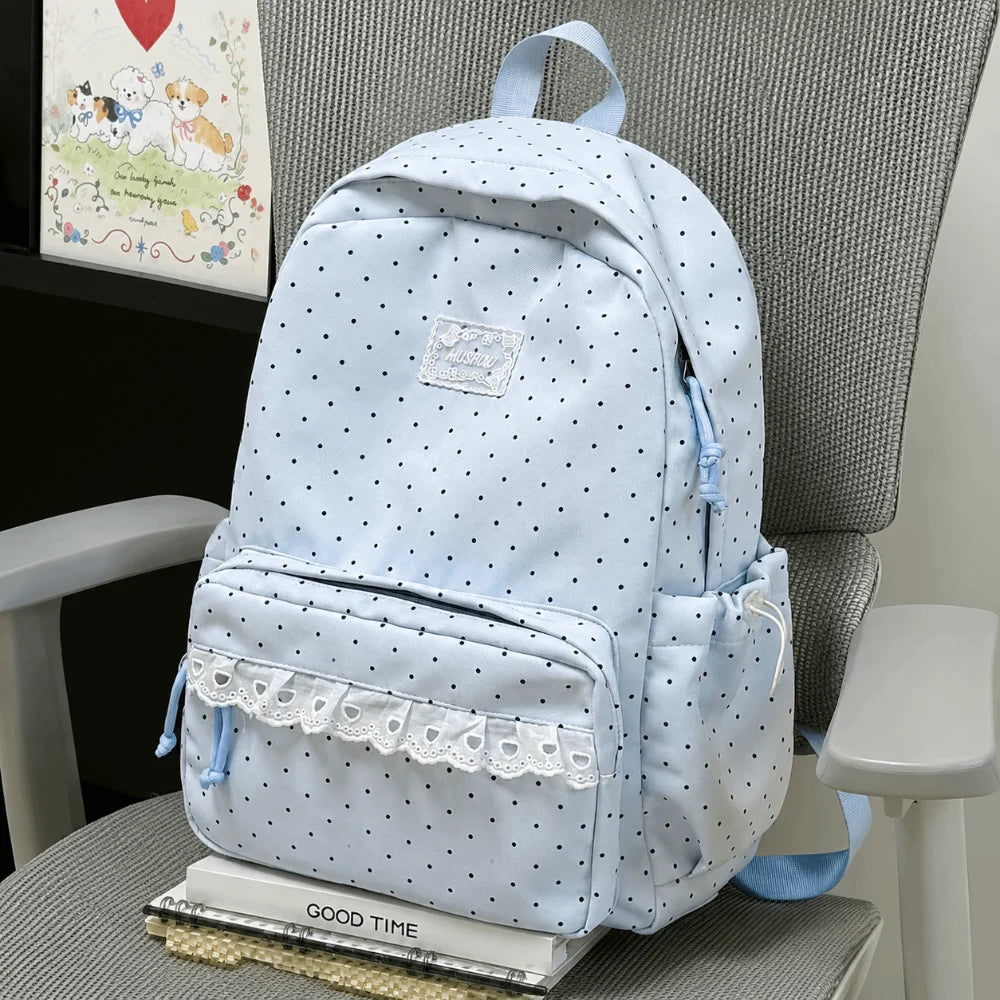 Light blue polka dot nylon travel backpack with a laptop compartment sitting on a gray chair.
