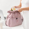 A person is holding a pink insulated lunch bag with a drawstring closure and a clear container of food.