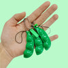 A hand holds several bright green, elongated fidget toy keychains with silver chains.