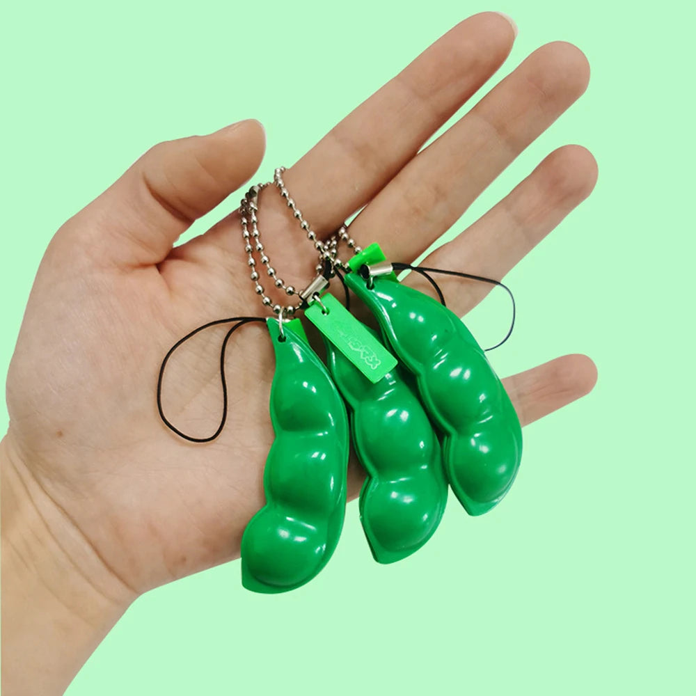 A hand holds several bright green, elongated fidget toy keychains with silver chains.